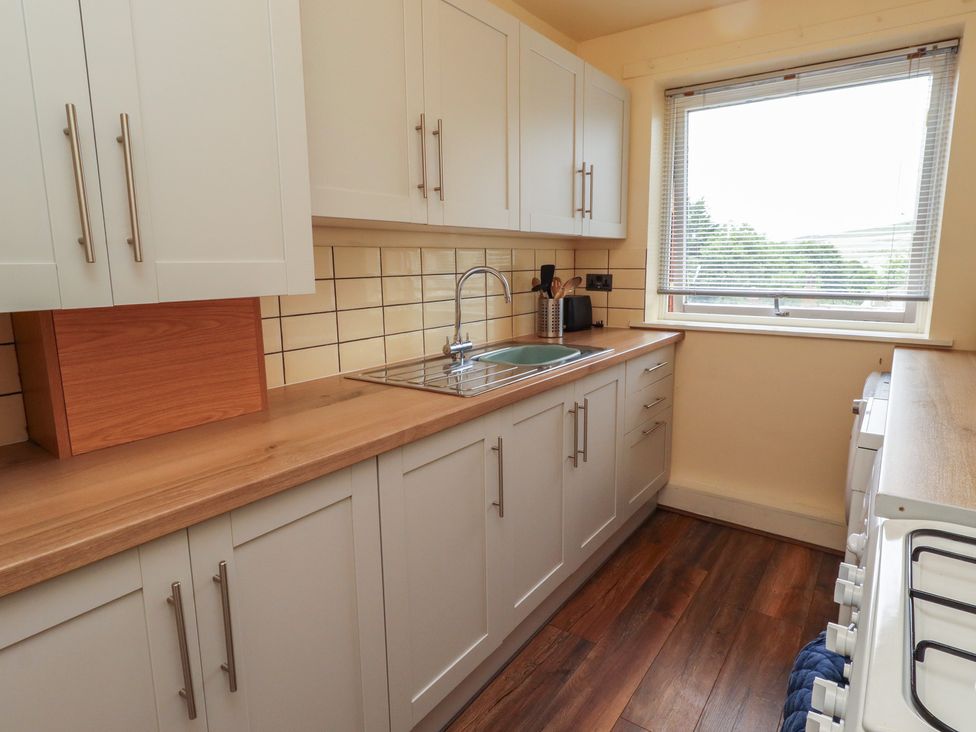 A kitchen with cabinets and sink at Flodden Apartment in Wooler