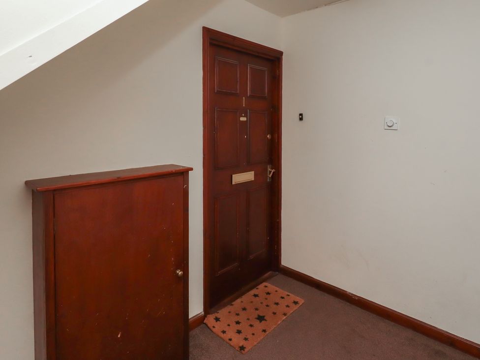A hallway with a front door and a storage cabinet at Flodden Apartment in Wooler