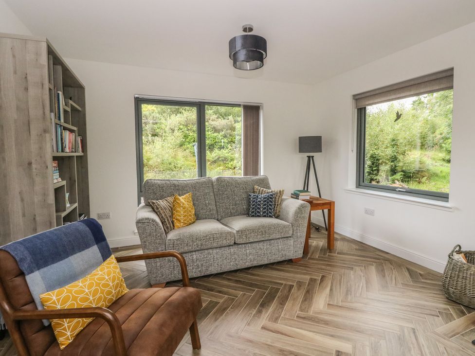 A living room with a sofa and bookshelves at Taigh Creag Thulach in Taynuilt