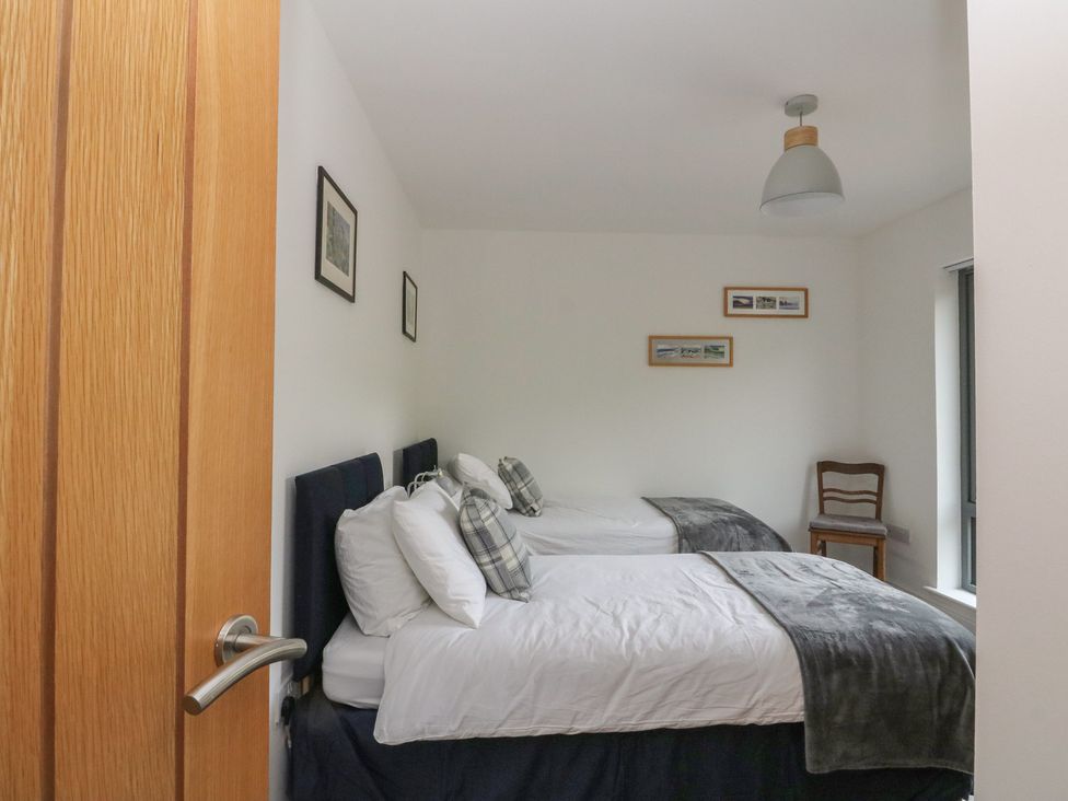 A bedroom with two beds and a chair at Taigh Creag Thulach in Taynuilt