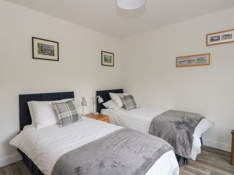 A bedroom with two beds and a nightstand at Taigh Creag Thulach in Taynuilt