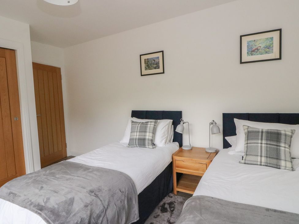 A bedroom with two beds and a bedside table at Taigh Creag Thulach in Taynuilt