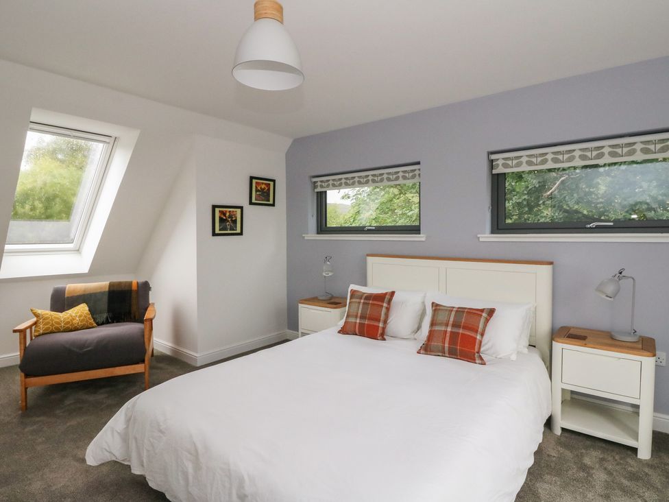 A bedroom with a bed and armchair at Taigh Creag Thulach Taynuilt