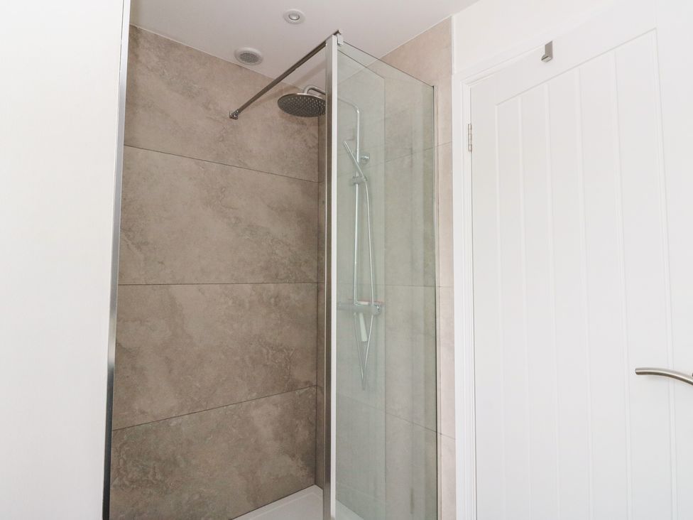 A shower with glass door and wall tiles at Taigh Creag Thulach Taynuilt