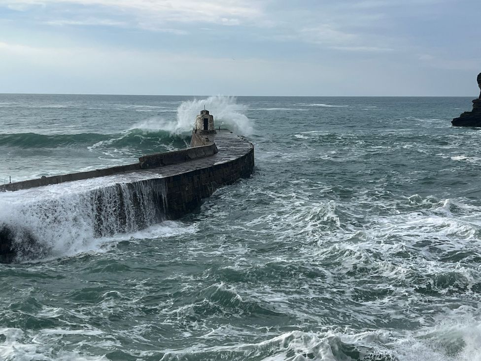 A stone pier with waves crashing against it in the ocean at Curnows in Portreath