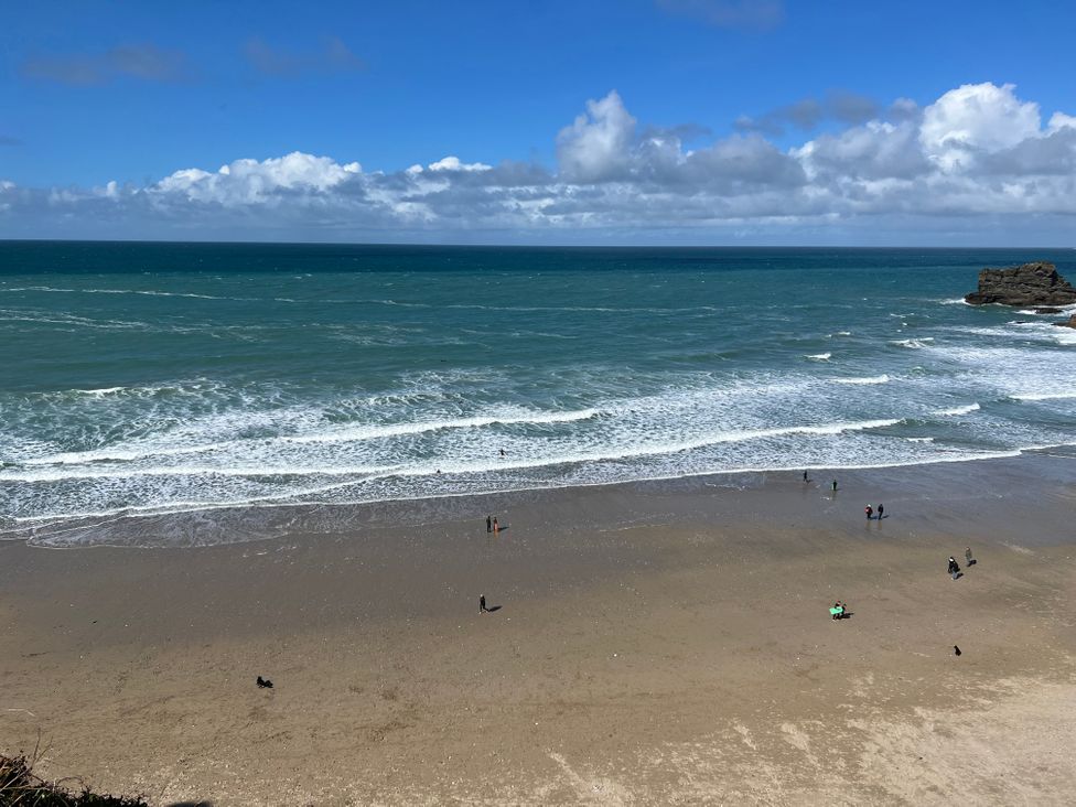 A beach with waves and people walking on the sand near the ocean at Curnows in Portreath