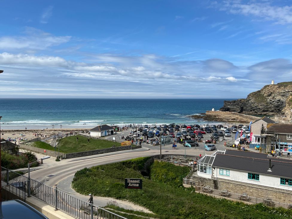 A coastal view with a parking lot near a beach and a rocky cliff at Curnows in Portreath