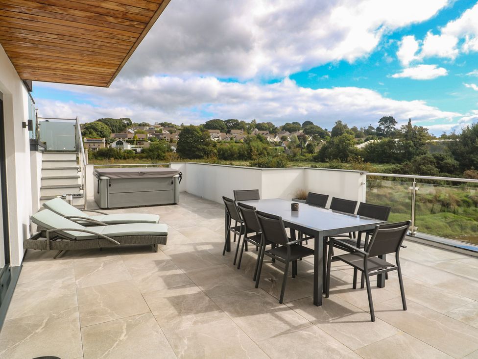 An outdoor terrace with seating and hot tub at Carnon Gwel, Devoran