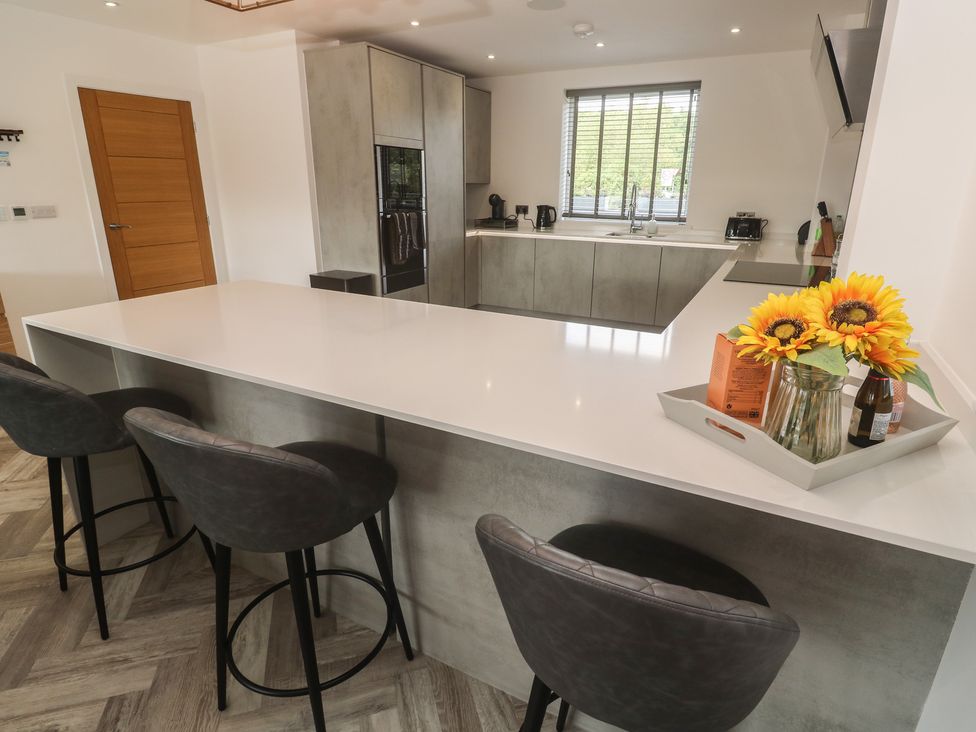 A kitchen with bar stools and a counter at Carnon Gwel, Devoran