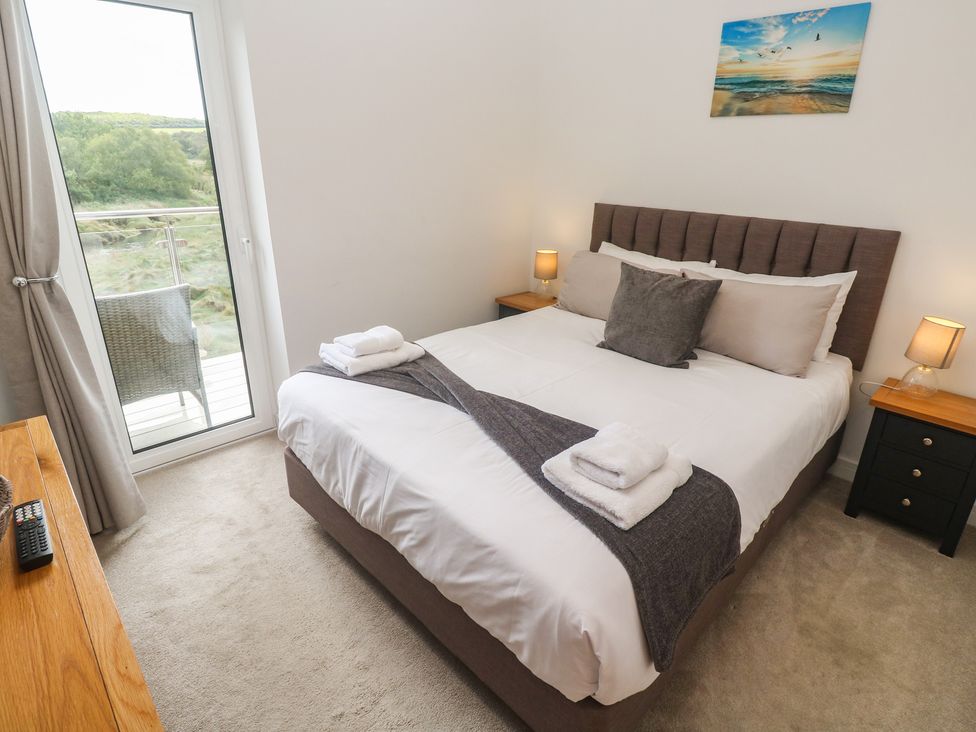 A bedroom with a bed and sliding door at Carnon Gwel, Devoran