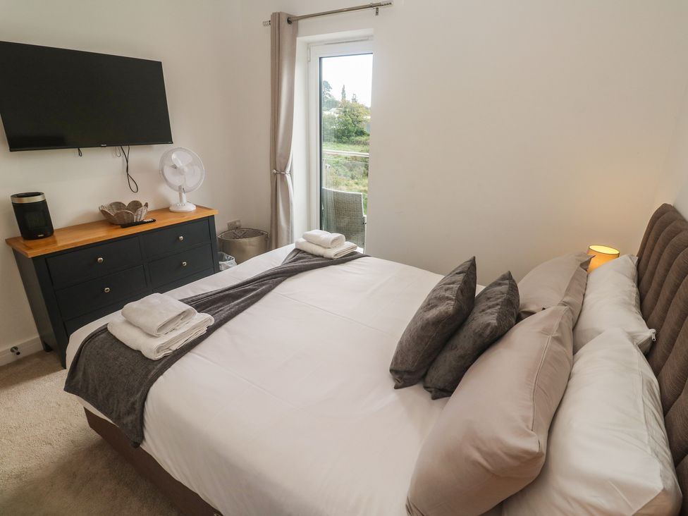 A bedroom with a bed and television at Carnon Gwel, Devoran