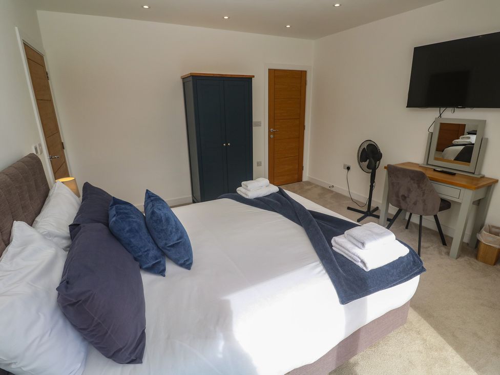 A bedroom with a bed and wardrobe at Carnon Gwel, Devoran