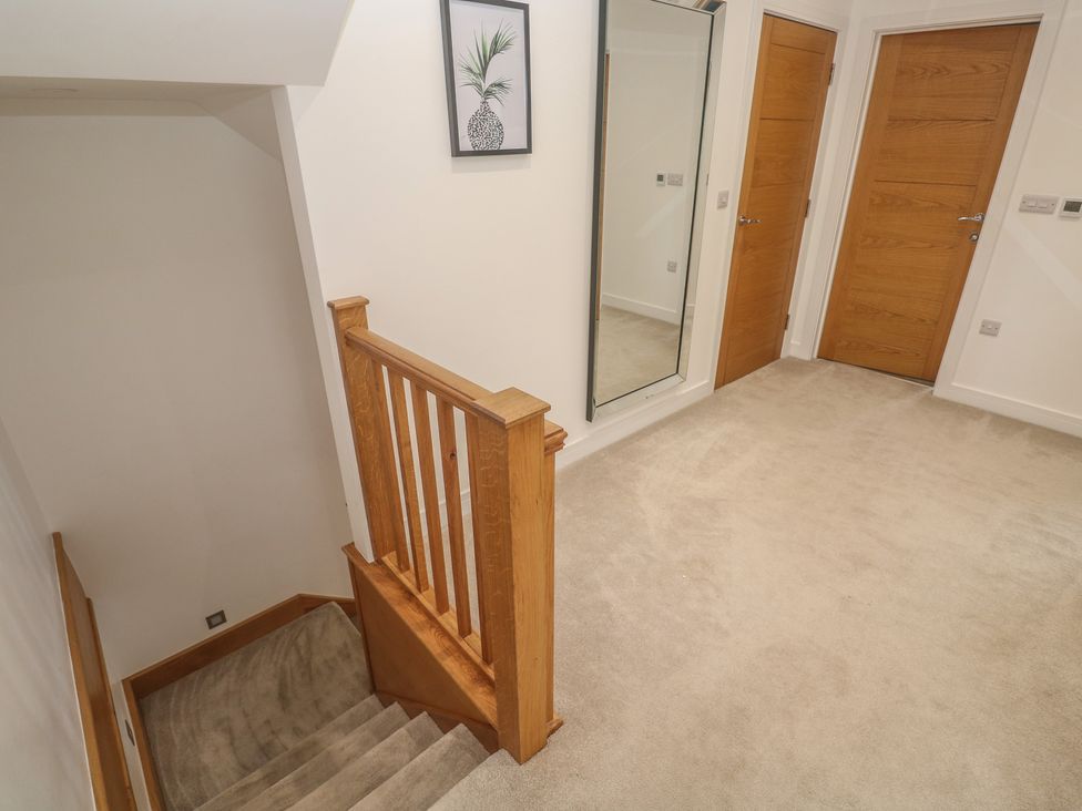 A hallway with a staircase and a mirror at Carnon Gwel, Devoran