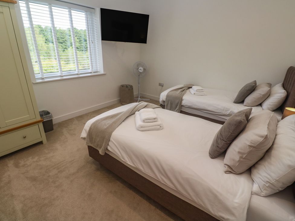A bedroom with twin beds and a television at Carnon Gwel, Devoran