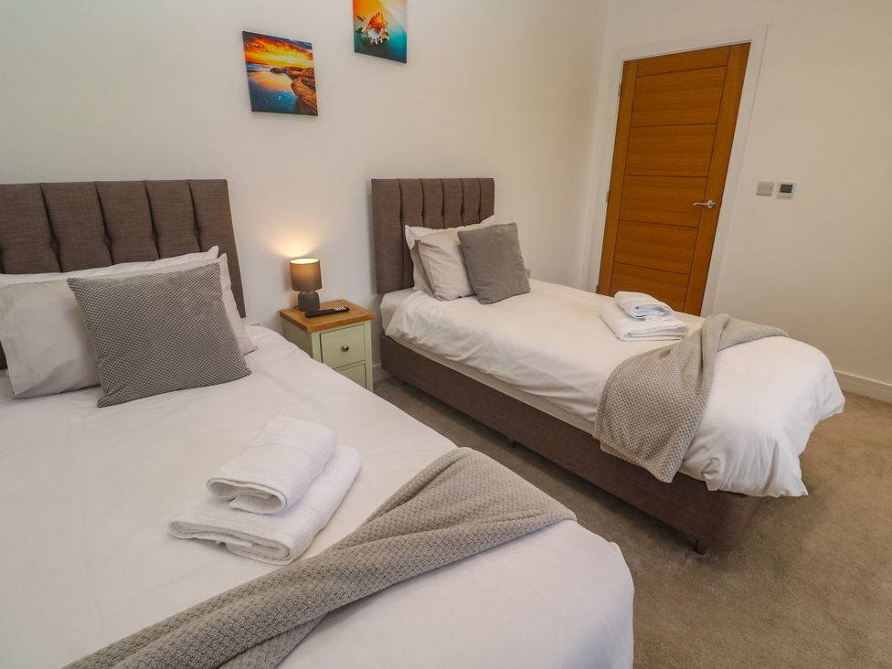A bedroom with two single beds and a lamp at Carnon Gwel, Devoran