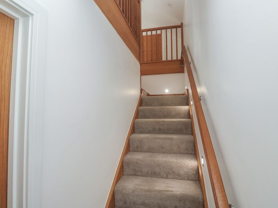A staircase with carpet and wooden handrails at Carnon Gwel, Devoran