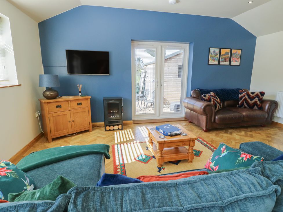 A living room with a sofa, coffee table, and TV at Trillo Lodge in Colwyn Bay