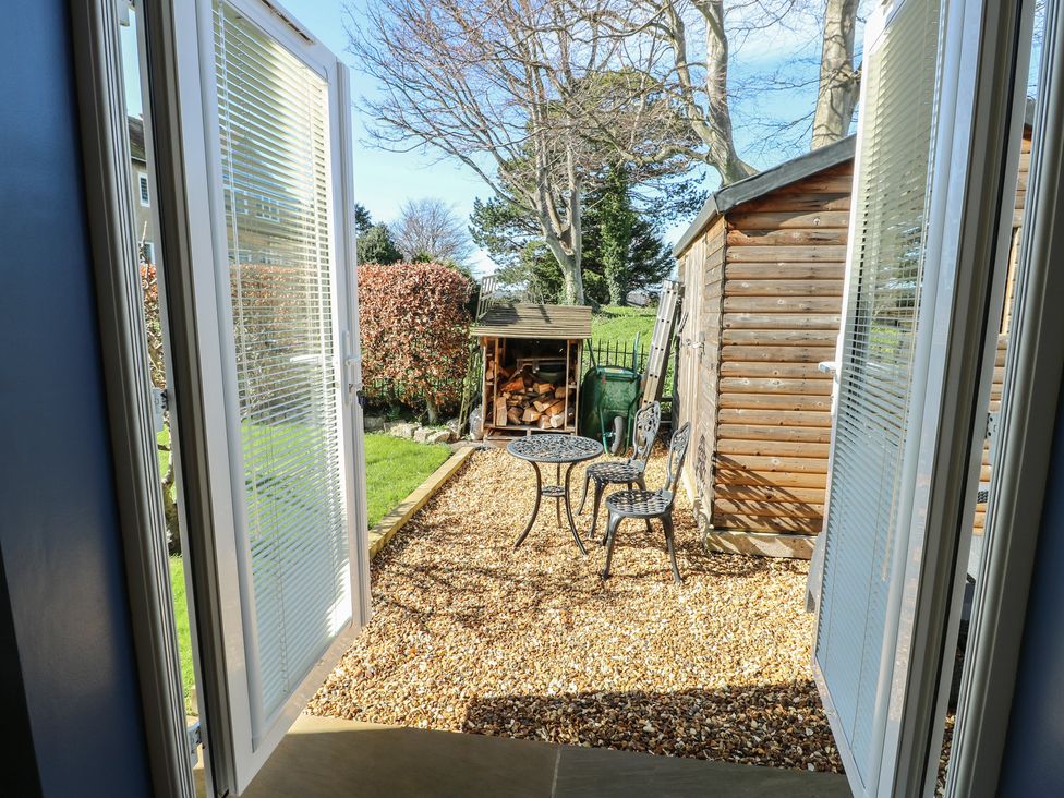 A garden view with a table and chairs and a shed at Trillo Lodge in Colwyn Bay