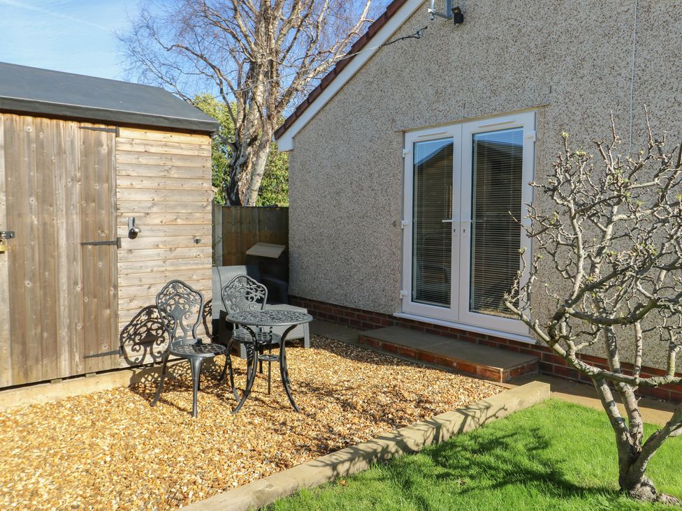A garden with a wooden shed and seating area at Trillo Lodge in Colwyn Bay