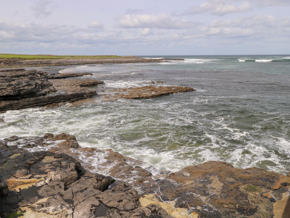 A rocky shoreline with waves by the ocean at Doonalton House in Dromore West, County Sligo