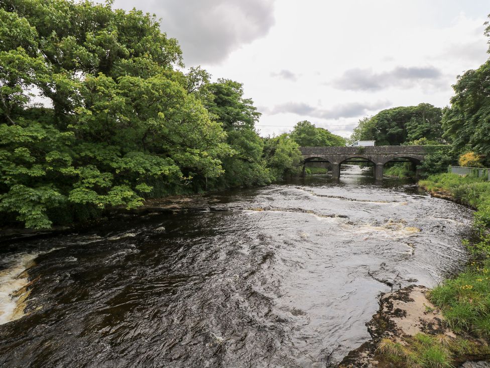 A river with a stone bridge and trees at Doonalton House in Dromore West, County Sligo