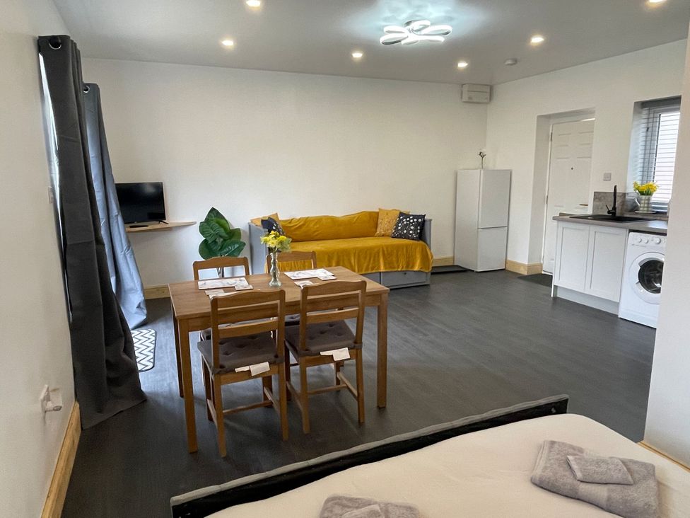 A living room with a sofa, table, and television at Daisy in Hannington near Northampton