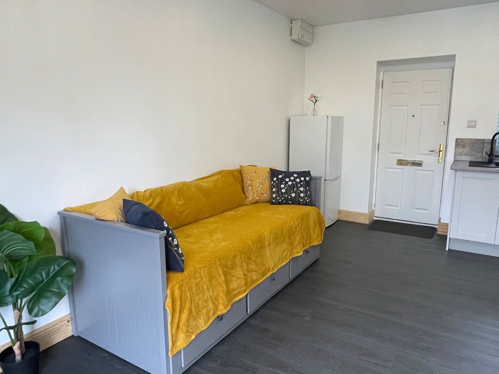 A living room with a yellow sofa and fridge at Daisy in Hannington near Northampton