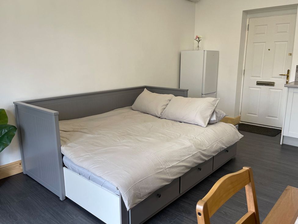 A living room with a bed, refrigerator, and a chair at Daisy in Hannington near Northampton