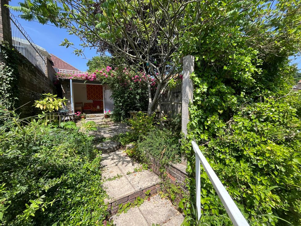 A garden pathway with greenery and a building at The Elbow in Frampton
