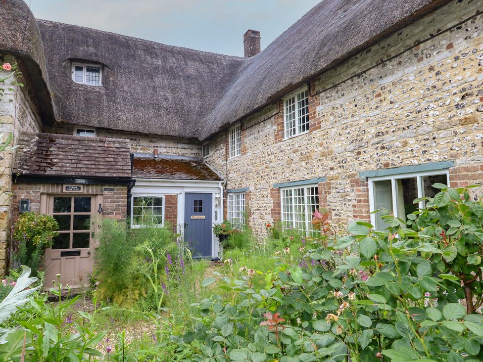 A cottage with a thatched roof and garden at The Elbow in Frampton