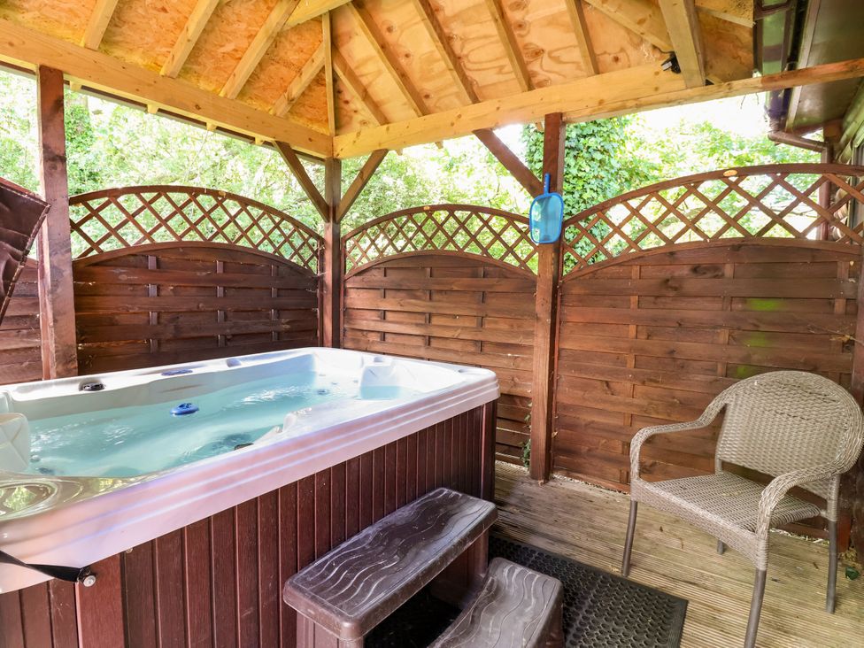 An outdoor area with a hot tub and a chair at The Red in Llanerch Park near St Asaph