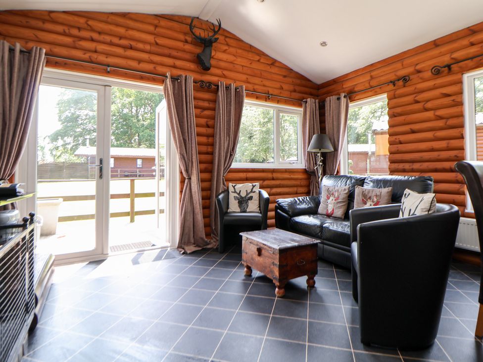 A snug with a leather sofa and wooden coffee table at The Fallows in Llanerch Park near St Asaph