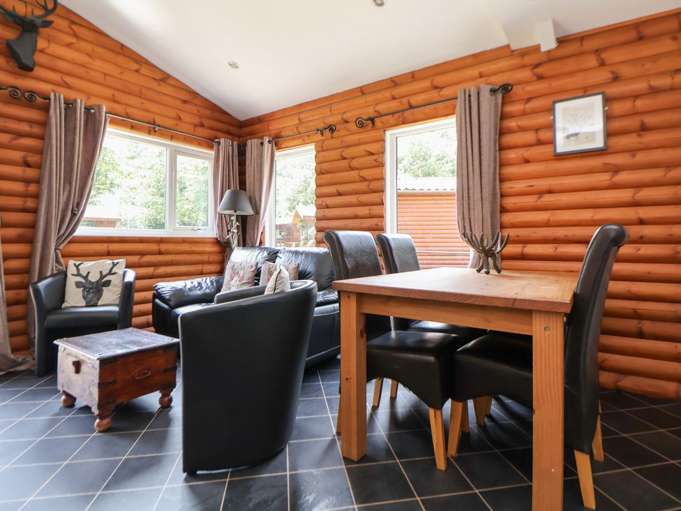 A living room with a sofa, coffee table, and dining table at The Fallows in Llanerch Park near St Asaph