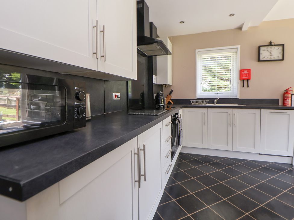 A kitchen with cabinets and a microwave at The Fallows in Llanerch Park near St Asaph