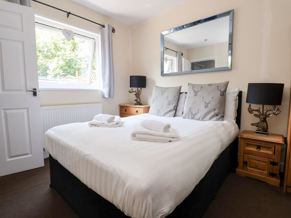 A bedroom with a bed, bedside tables, and lamps at The Fallows in Llanerch Park near St Asaph