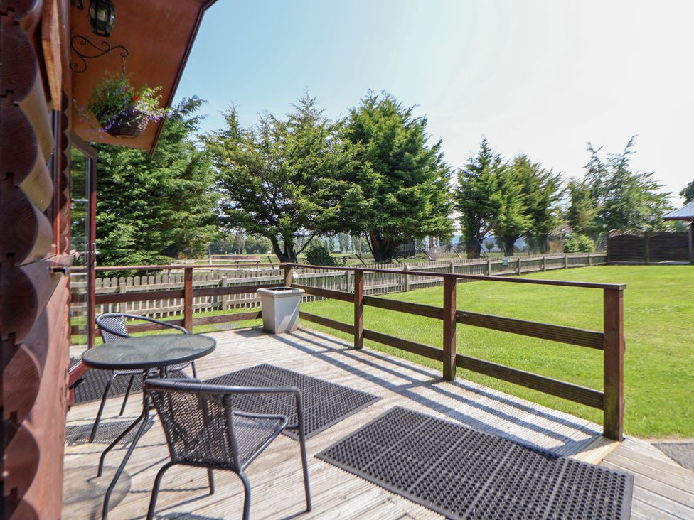 An outdoor area with deck, chairs and table at The Fallows in Llanerch Park near St Asaph
