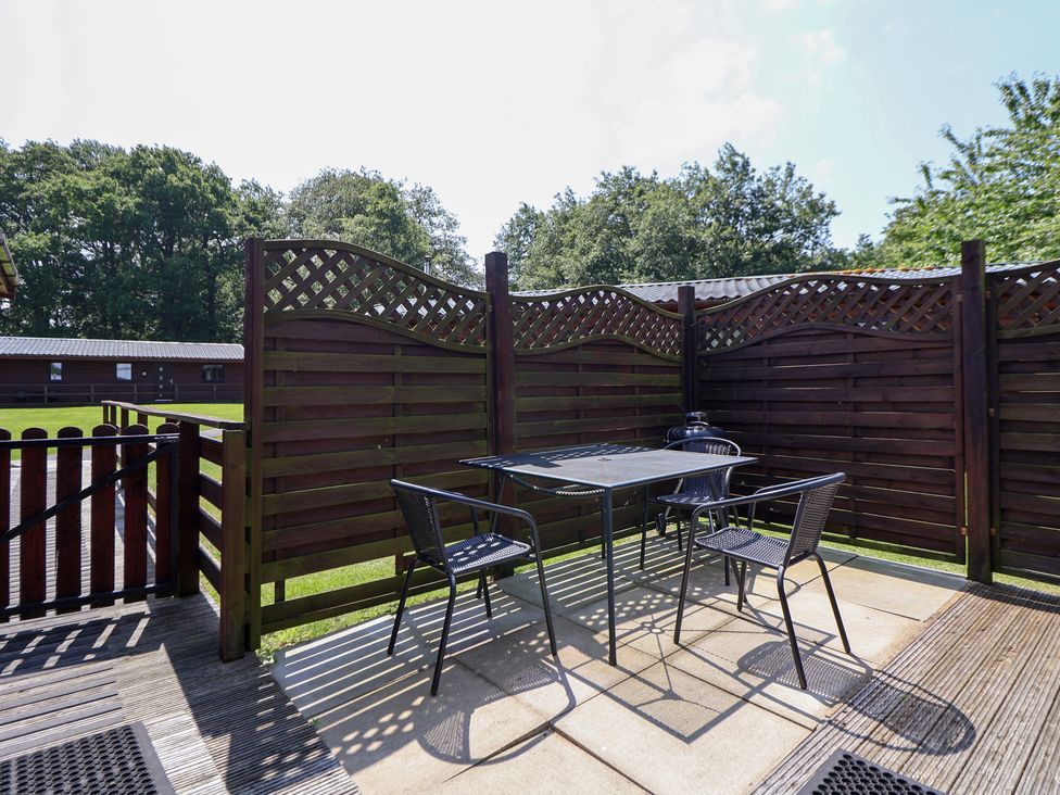 An outdoor patio with a table and chairs at The Fallows in Llanerch Park near St Asaph