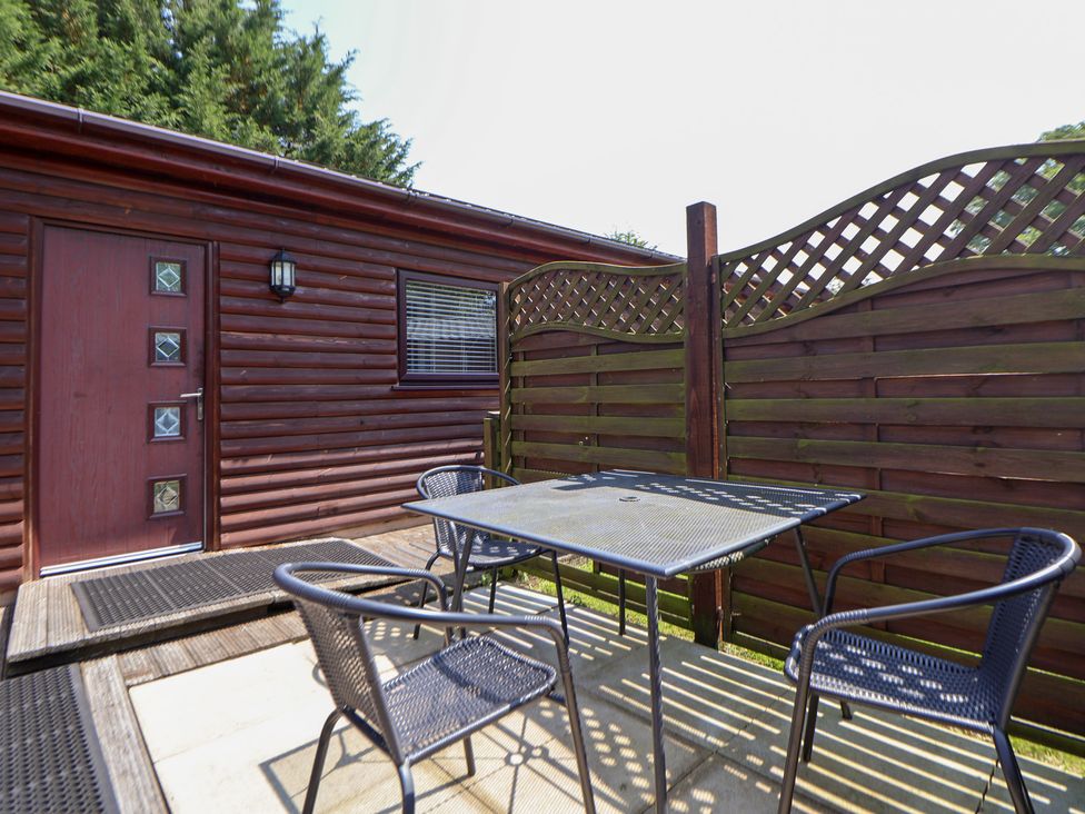 An outdoor seating area with a table and chairs at The Fallows near Llanerch Park St Asaph