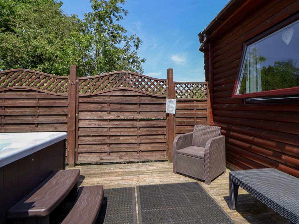 An outdoor area with a hot tub and seating at The Fallows Llanerch Park near St Asaph