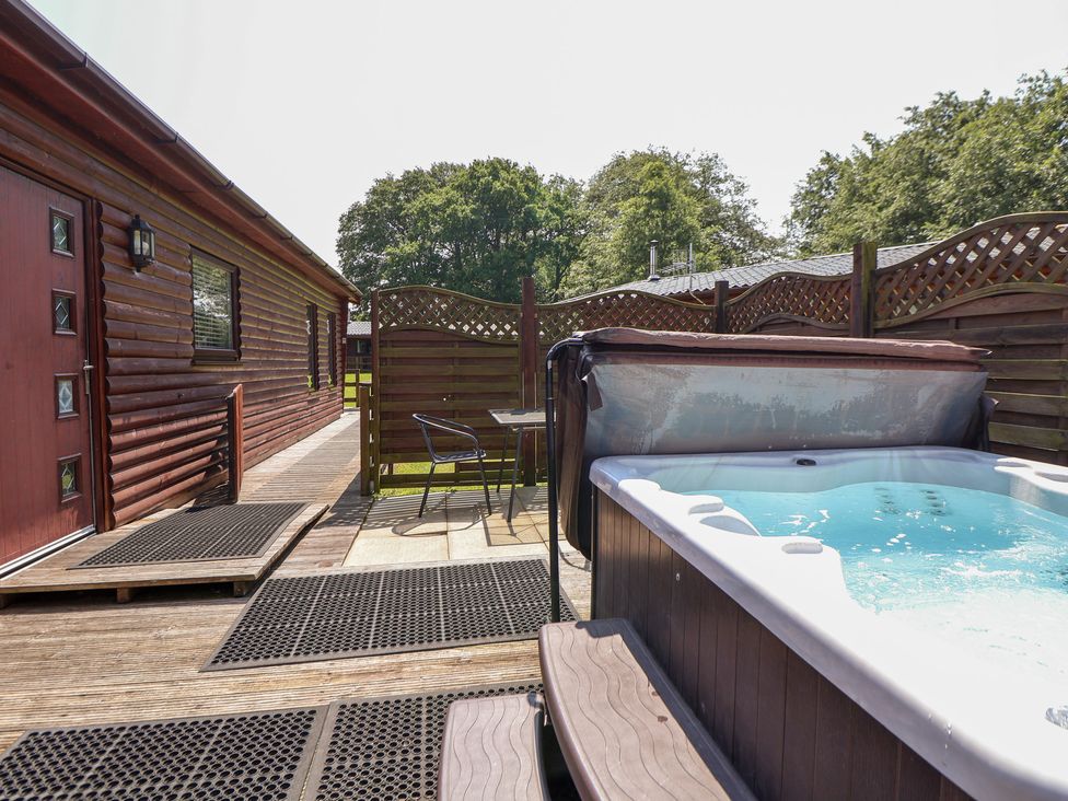 An outdoor area with a hot tub and seating at The Fallows in Llanerch Park near St Asaph