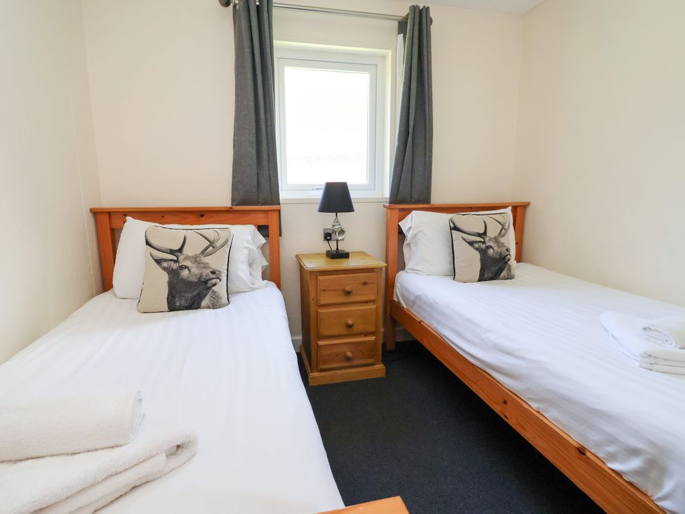 A bedroom with two single beds and a nightstand at The Roe in Llanerch Park near St Asaph