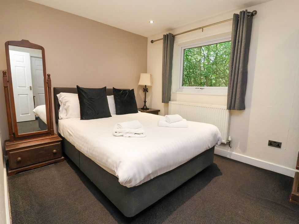 A bedroom with a bed, mirror and window at The Roe, Llanerch Park near St Asaph