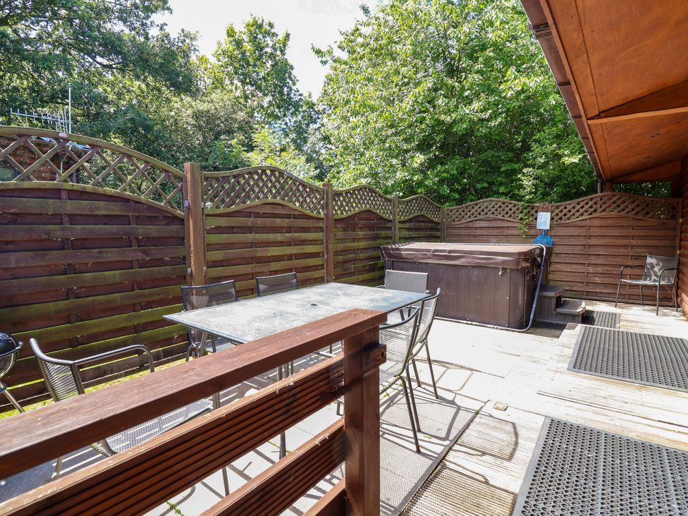 An outdoor seating area with a dining table and hot tub at The Roe Llanerch Park near St Asaph