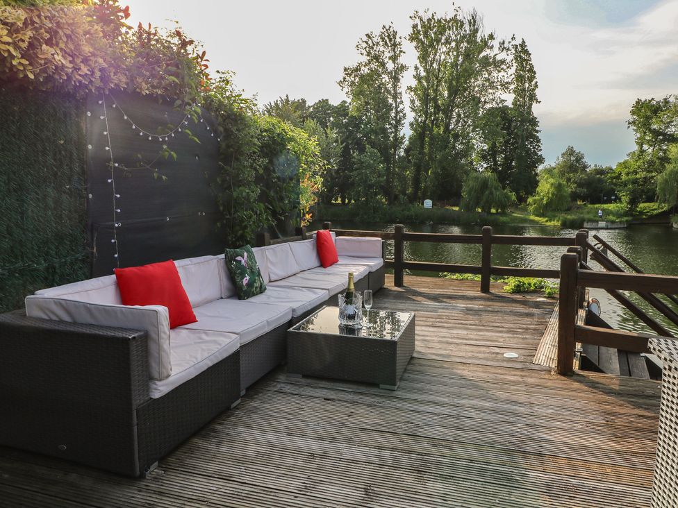 An outdoor seating area with a coffee table and view of the river at Coventina in Wraysbury