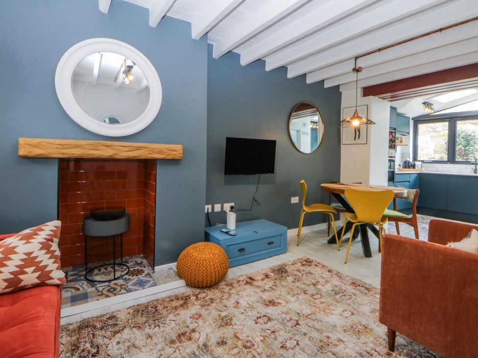 A living room with a fireplace and dining table at East meets West in Criccieth
