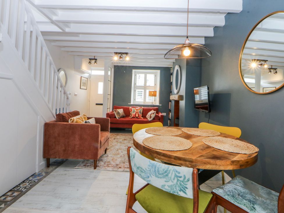 A living room with a sofa and dining table at East meets West in Criccieth