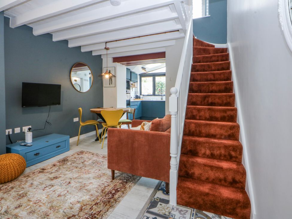 A living room with a staircase and dining area at East meets West in Criccieth