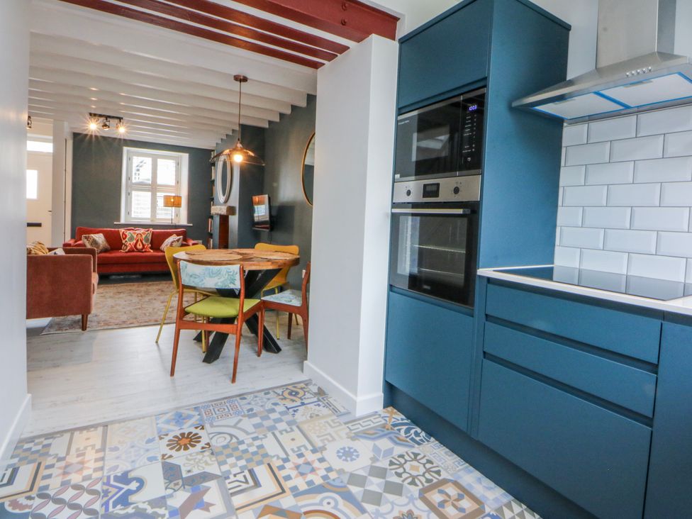 A kitchen with cabinets and a dining table at East meets West Criccieth