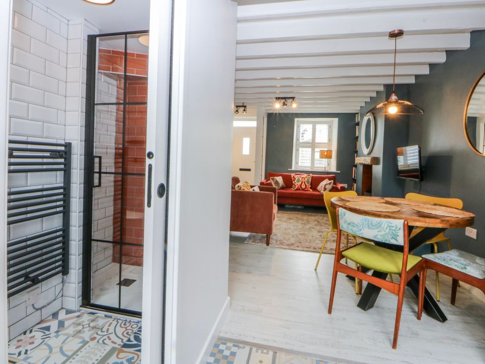 A living room with a sofa and dining area at East meets West in Criccieth