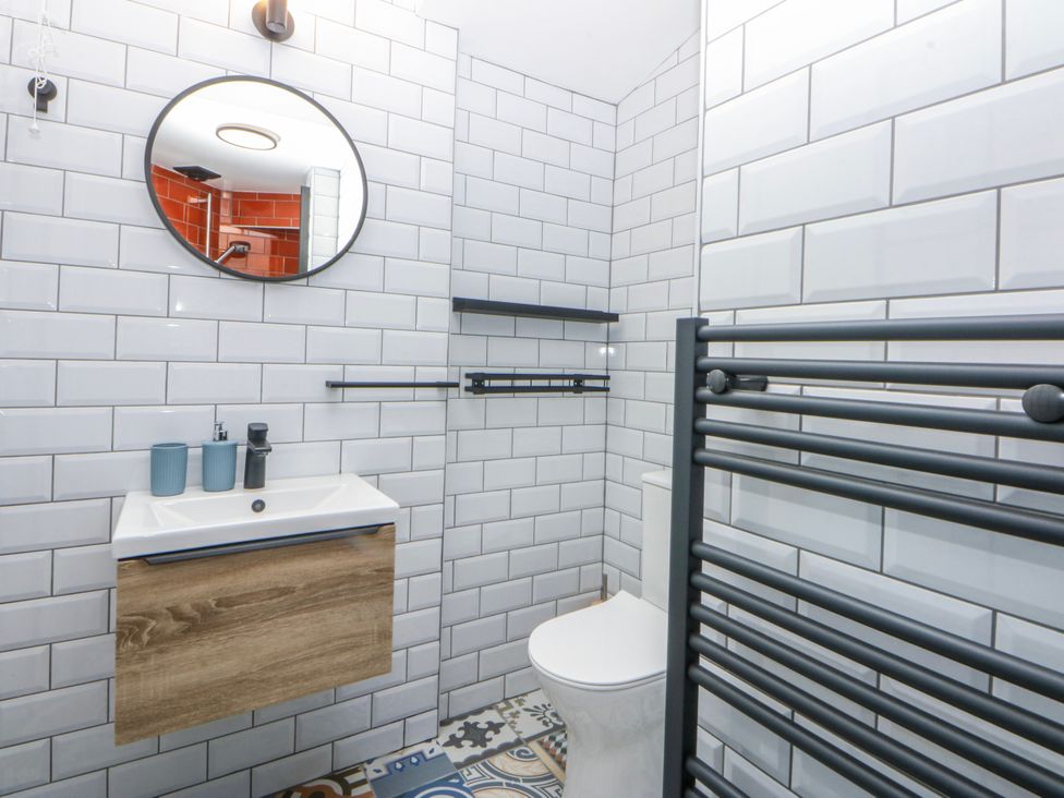 A bathroom with a sink, toilet, and mirror at East meets West in Criccieth